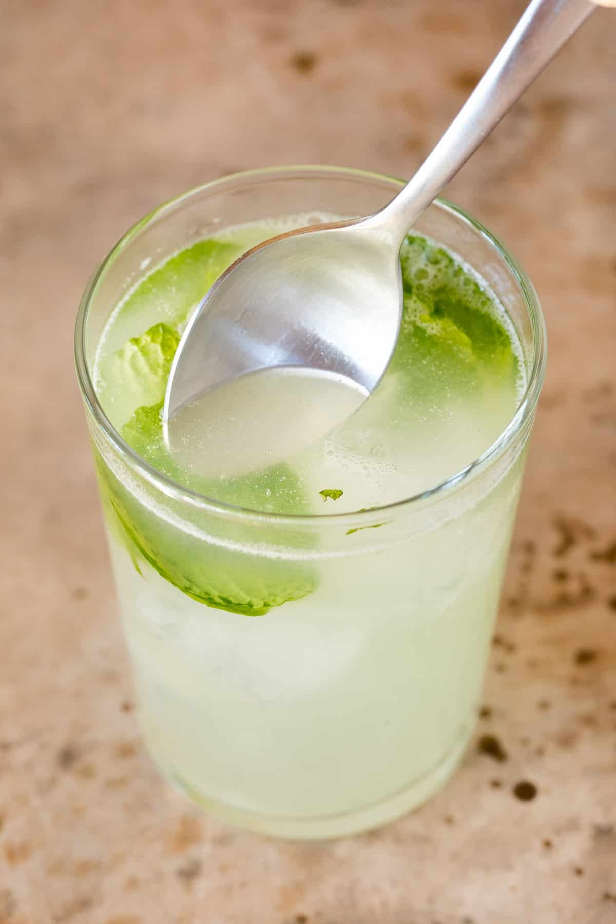 A spoon in a drink stirring it.