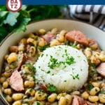 A bowl of slow cooker black eyed peas garnished with parsley and a scoop of rice.