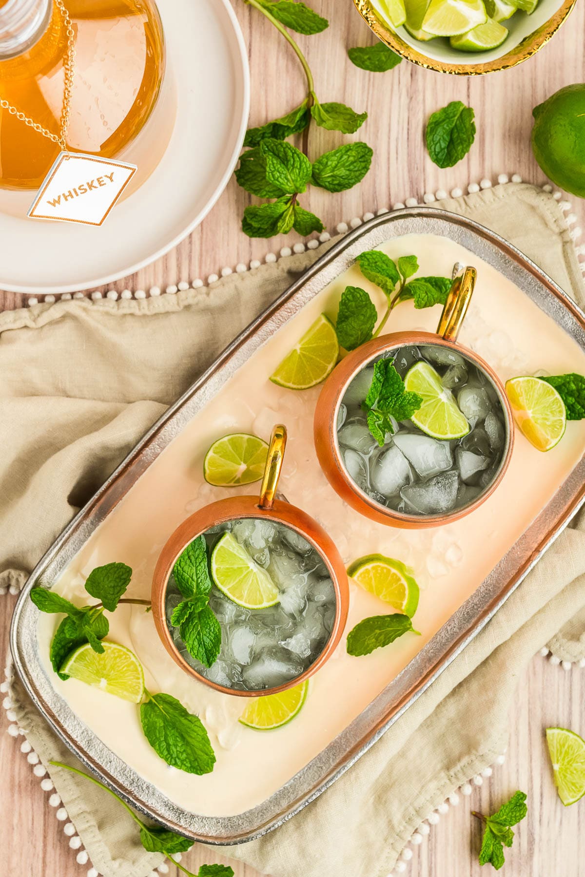 Two Irish drinks on a platter garnished with lime slices and fresh mint.