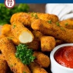 Homemade mozzarella sticks on a plate with marinara sauce.