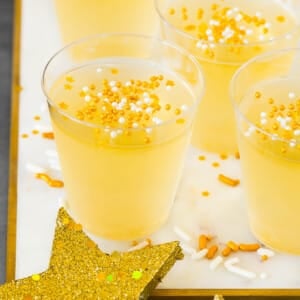 Champagne Jello shots on a marble tray with sprinkles on top.
