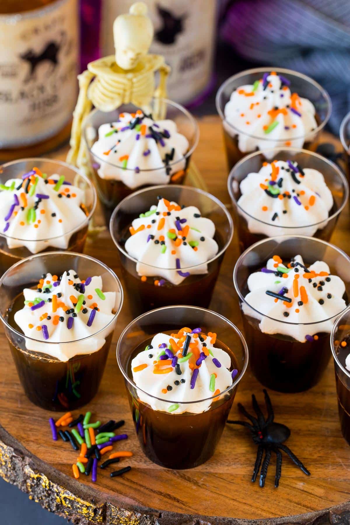 Halloween Jello shots on a serving platter with whipped cream and sprinkles on top.