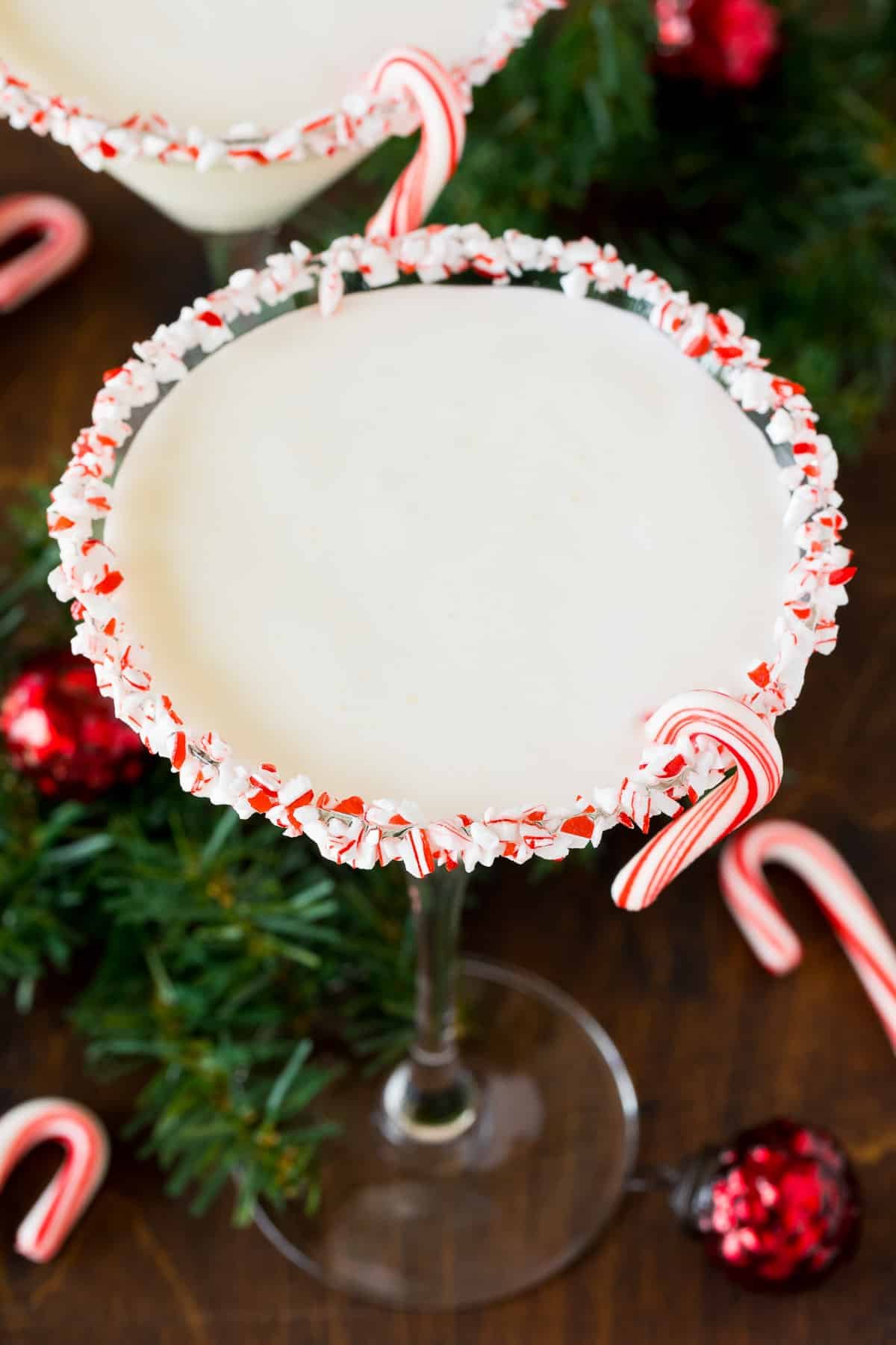 A glass of peppermint martini with a candy cane garnish.