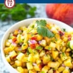 A bowl of peach salsa garnished with cilantro.