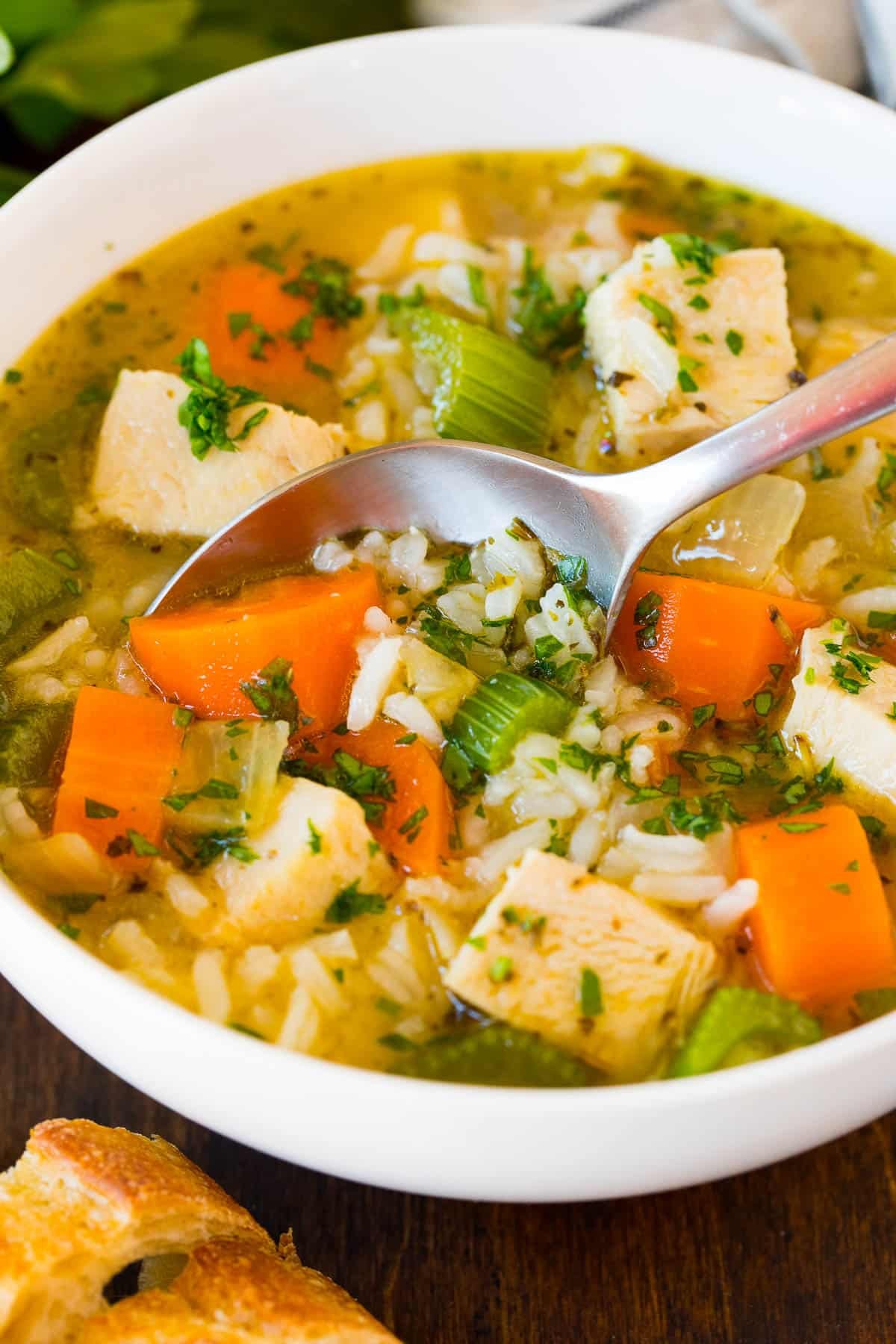 A bowl of turkey and rice soup with a spoon in it.