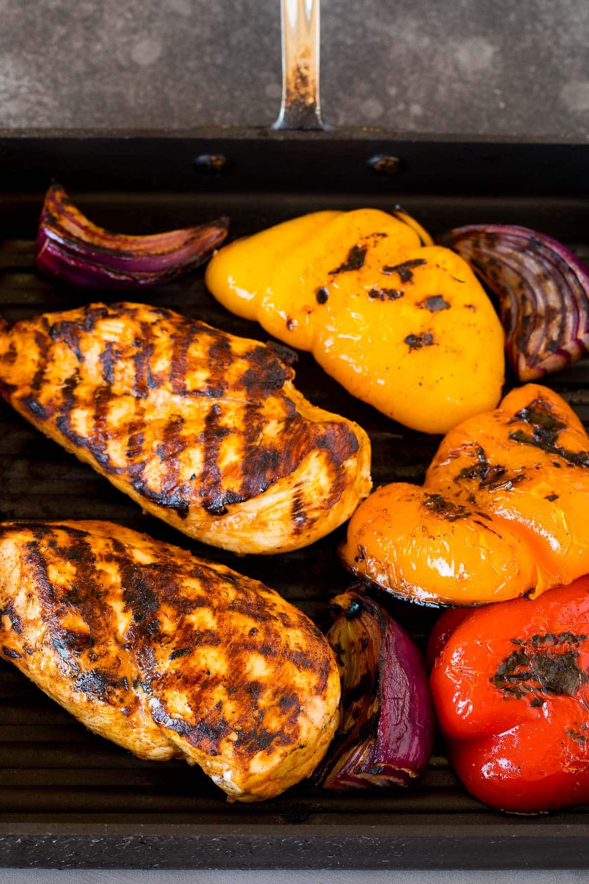 Chicken, bell peppers and onions on a grill pan.