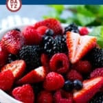A bowl of berry fruit salad topped with honey lime poppyseed dressing.