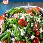 A bowl of green bean salad featuring cherry tomatoes and feta cheese.
