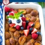 A baking dish full of donut bread pudding topped with fresh berries.