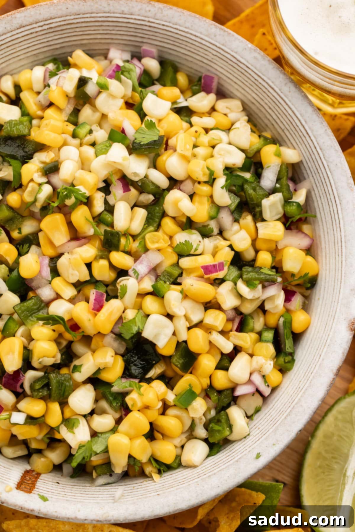 Overhead view of a white bowl of roasted chili corn salsa on a table.