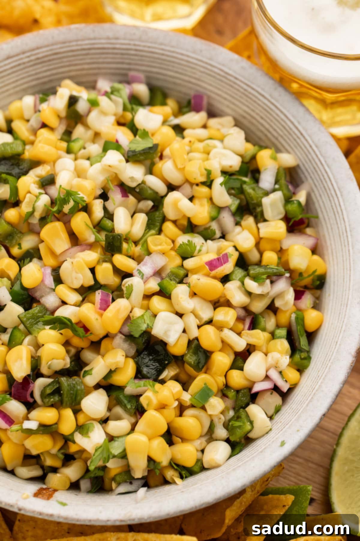 Overhead view of a white bowl of roasted chili corn salsa on a table.