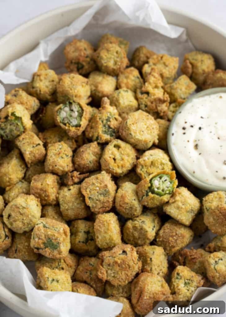 Air fryer okra in a bowl next to a small bowl of lemon garlic aioli