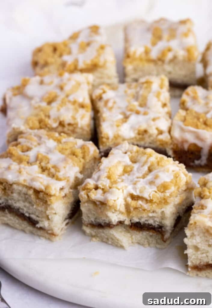 Squares of vegan coffee cake with streusel topping and glaze on a white plate, ready to serve