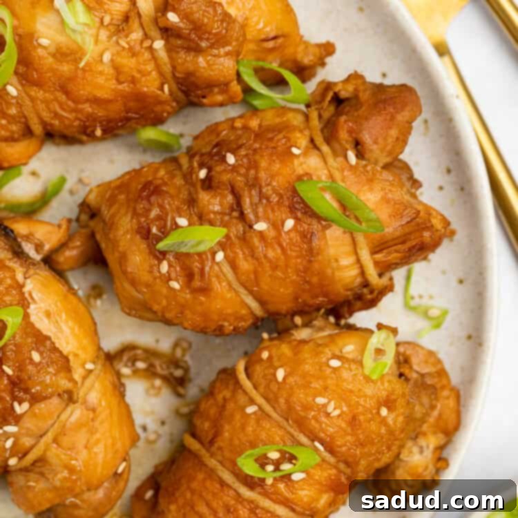 chicken chashu on a plate with sliced scallions and sesame seeds on top