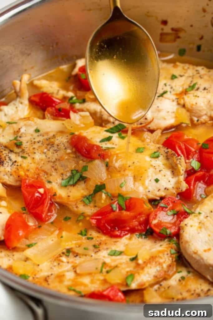 sauce being spooned over a skillet of chicken pomodoro
