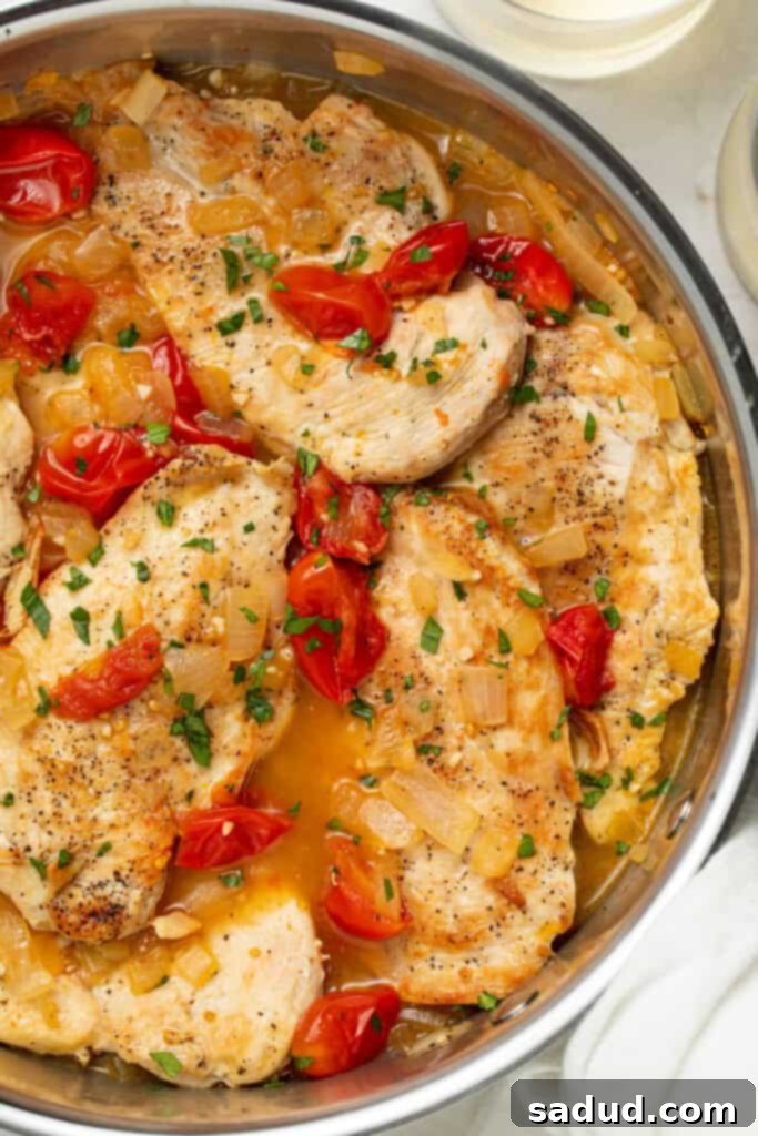 overhead image of chicken pomodoro in a skillet with white wine on the side