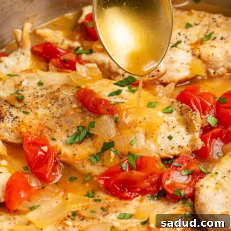 sauce being spooned over a skillet of chicken pomodoro