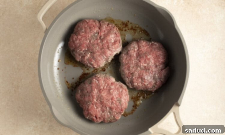 Buffalo burger patties sizzling in a large skillet
