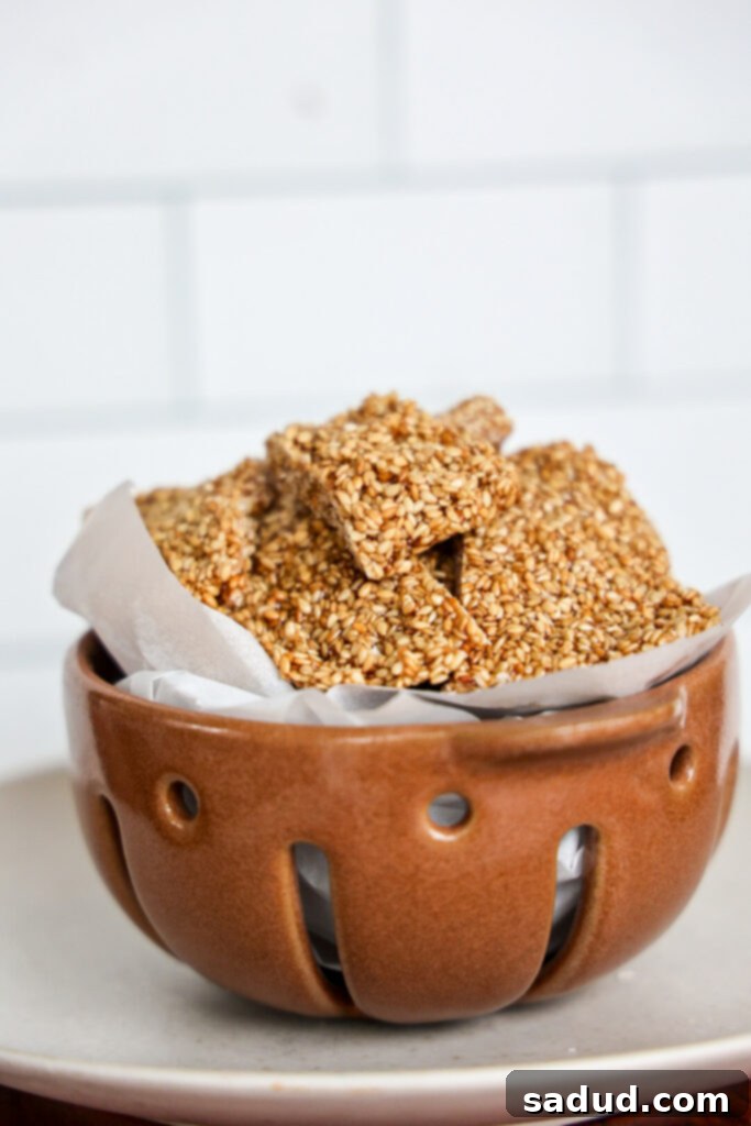 Close-up of golden honey sesame seed candy pieces on a light background, highlighting its texture and inviting appeal.