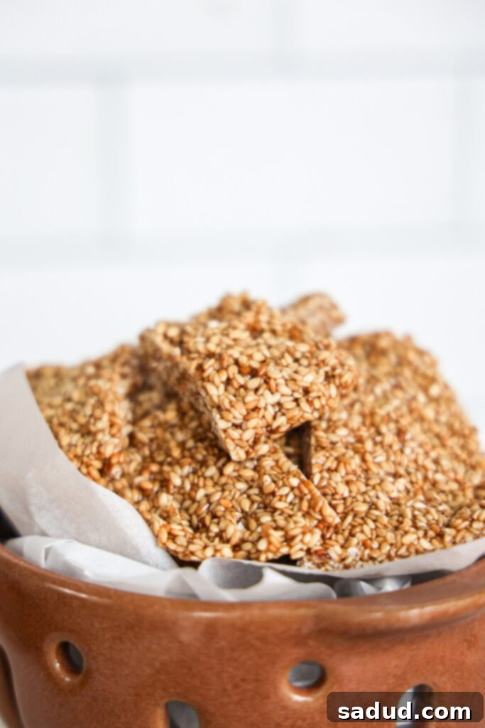 A bowl filled with golden-brown maple sesame seed candy, with some pieces scattered around, suggesting a delicious and wholesome snack.