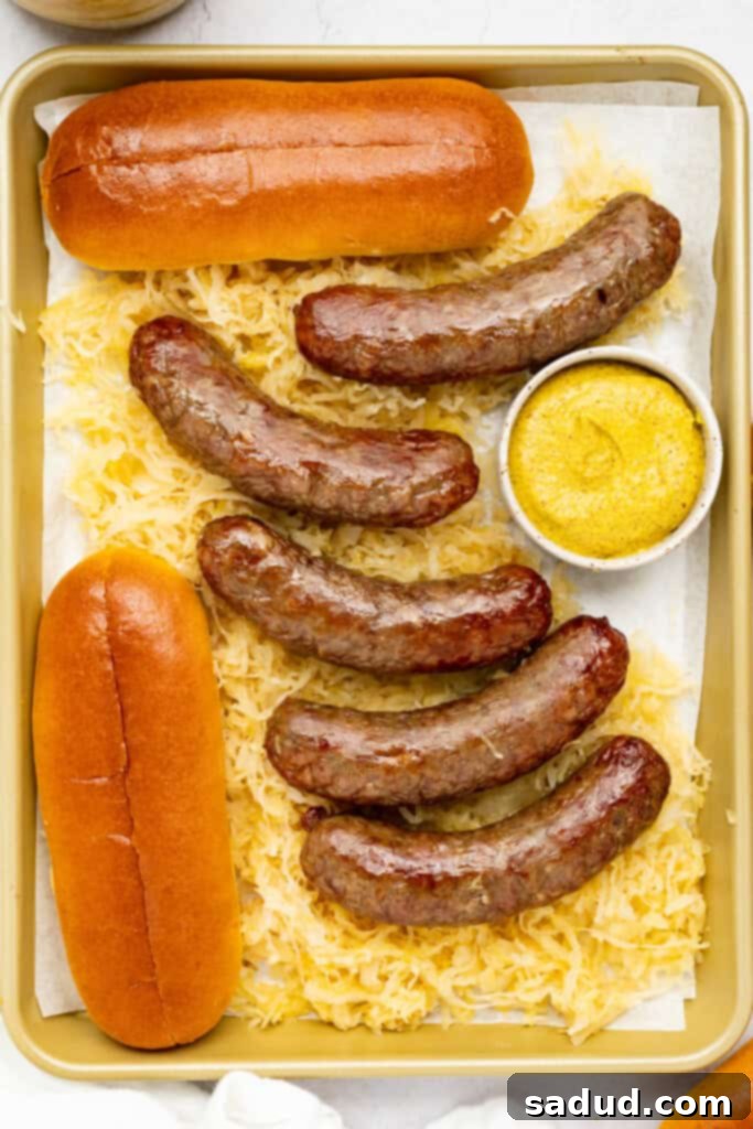 air fryer brats on a baking sheet with sauerkraut, mustard, and buns
