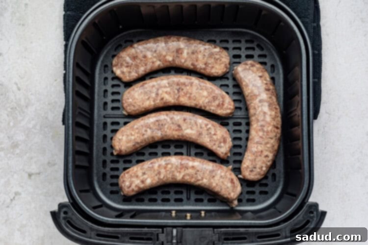 Brats being placed in a single layer in an air fryer basket
