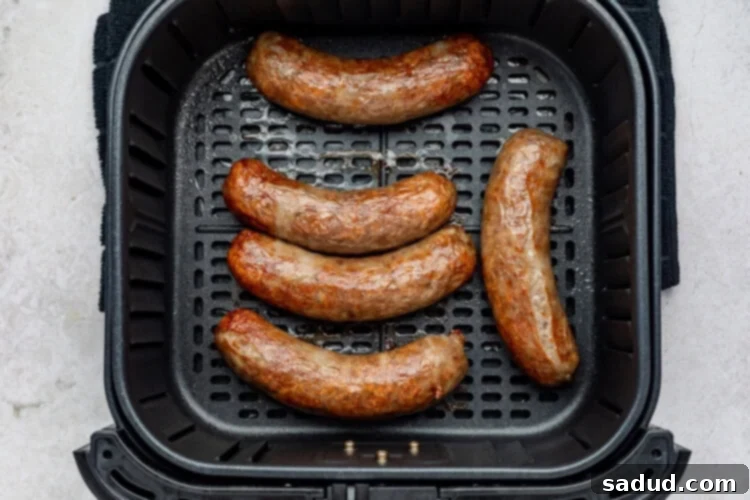 Cooked air fryer brats being removed from the air fryer with tongs