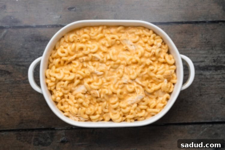 Overhead view of macaroni and cheese in a casserole dish on a wooden background, prior to baking.
