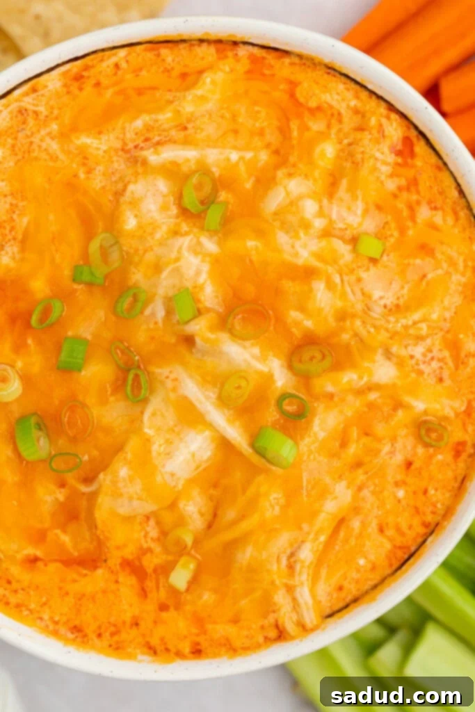 An overhead close-up of a bowl of creamy Instant Pot buffalo chicken dip, garnished with finely sliced green onions, ready to be served.