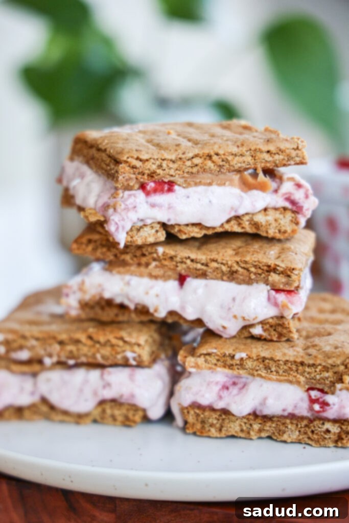 Delicious Strawberry Frozen S'mores with a creamy filling and peanut butter magic shell on a wooden board.