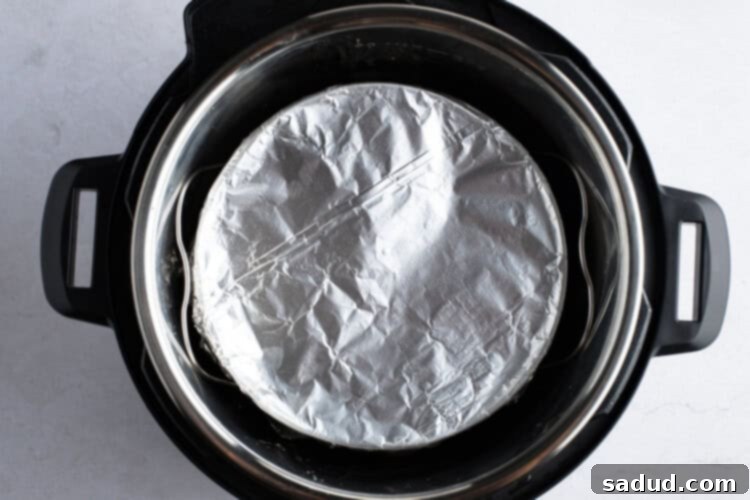 Instant Pot setup with trivet, water, and foil-covered cornbread pan inside