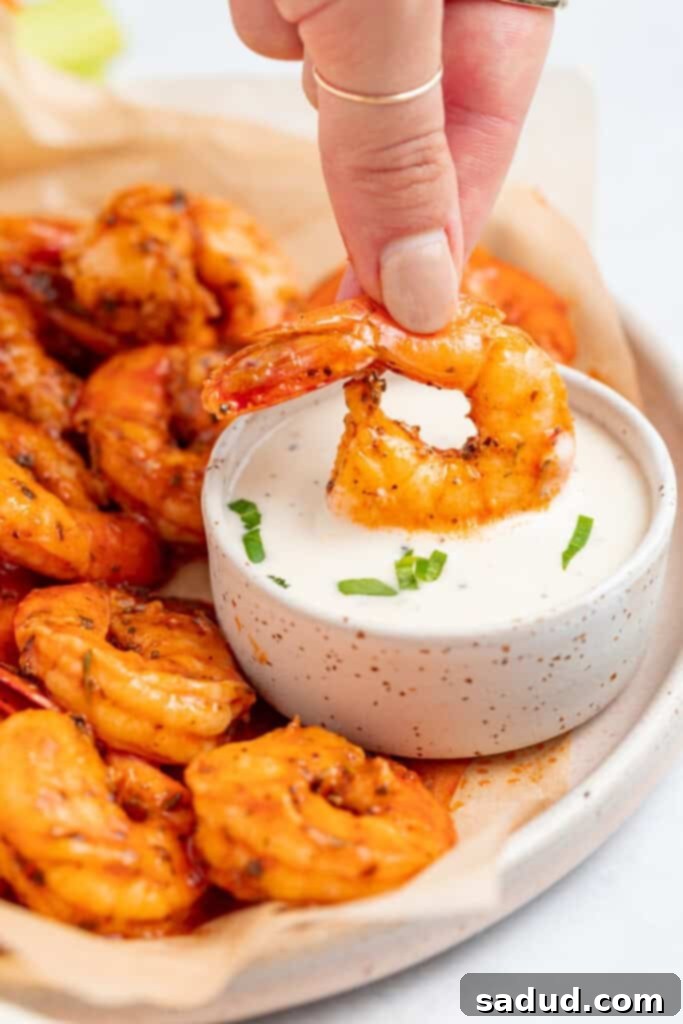 buffalo shrimp being dipped into a bowl of ranch dressing