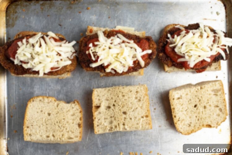 Chicken parm sandwiches on baking sheet, cheese melted and ready to serve.