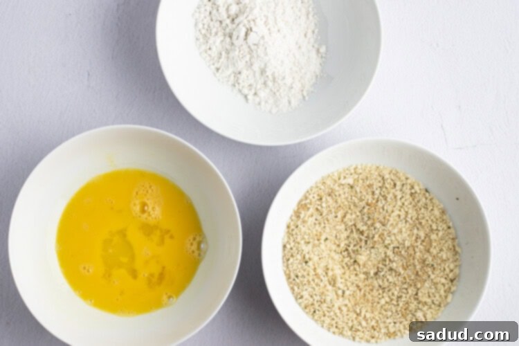 Breading ingredients for chicken parm sandwich in shallow bowls.