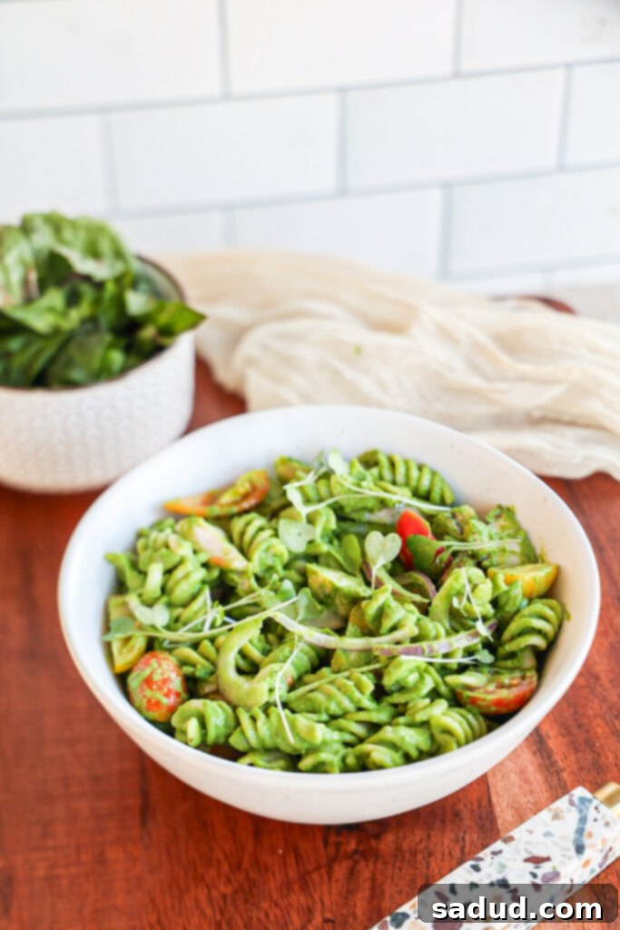 Ingredients for Green Goddess Pasta Salad including pasta, tomatoes, onion, avocado, and dressing ingredients.