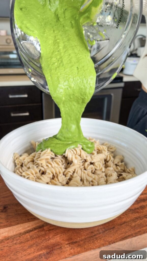 A bowl of Green Goddess Pasta Salad, garnished with fresh herbs and a fork.