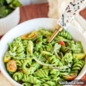 A top-down view of Green Goddess Pasta Salad in a bowl, showing the vibrant green dressing and fresh ingredients.