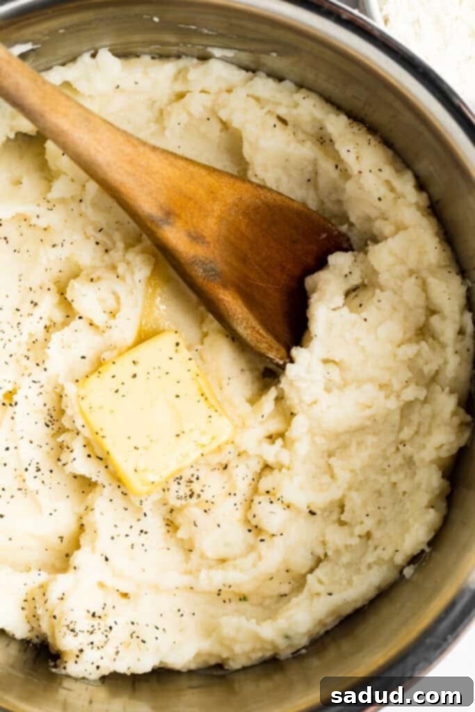 overhead image of mashed potatoes in a pot with butter and a wooden spoon, perfectly thickened and ready to serve