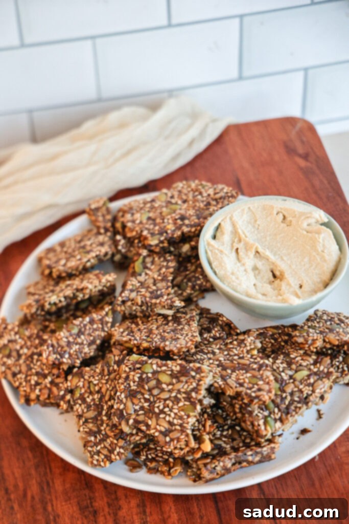 healthy homemade seed crackers with sesame, pumpkin, flax, and sunflower seeds and hummus.
