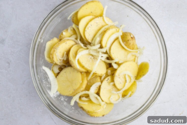 Floured potatoes and onions in large glass bowl