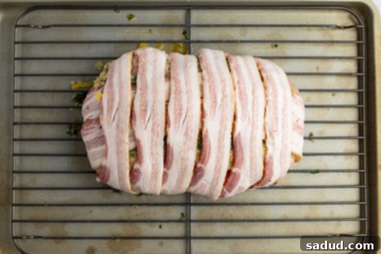 Uncooked bacon wrapped turkey breast on a baking rack