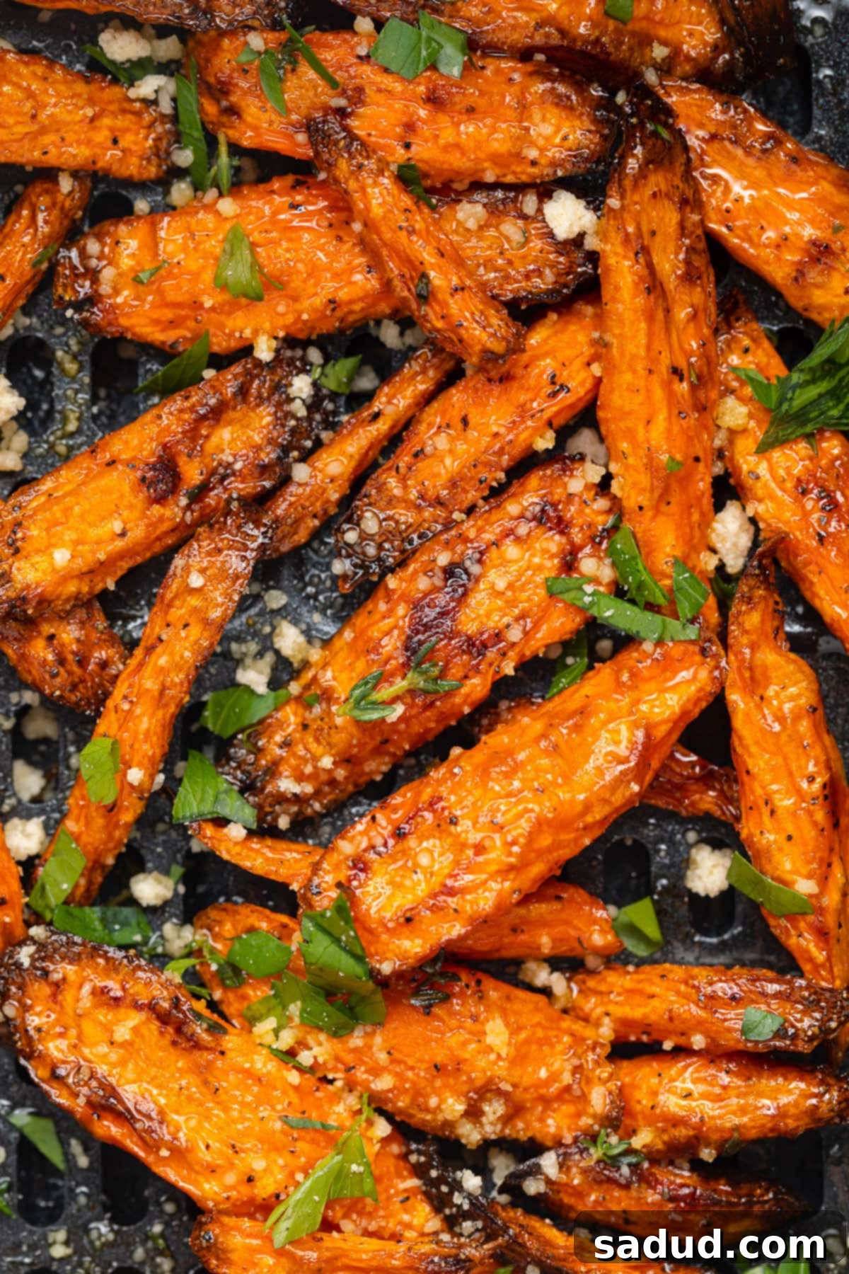 Air fryer carrots in an air fryer basket, showing golden-brown edges.