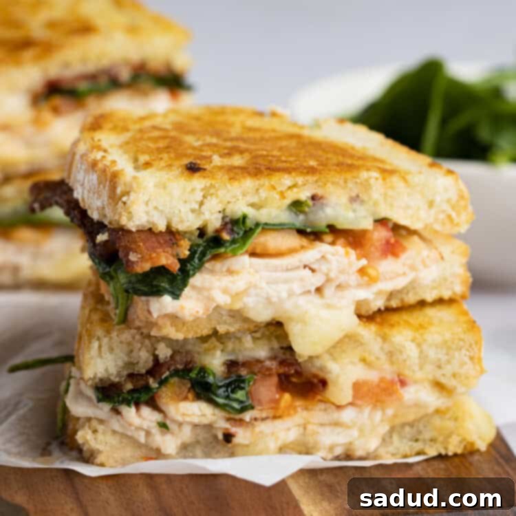 Two halves of a turkey melt stacked on top of each other, on a wooden tray