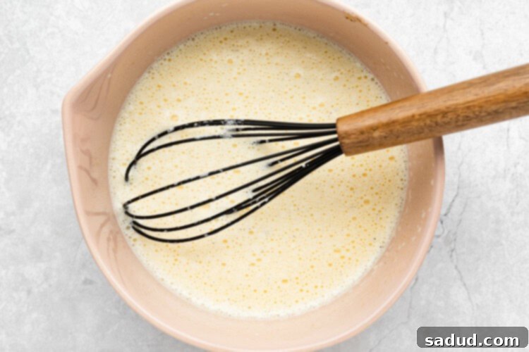 slowly pouring hot cream into egg yolk mixture for keto creme brulee