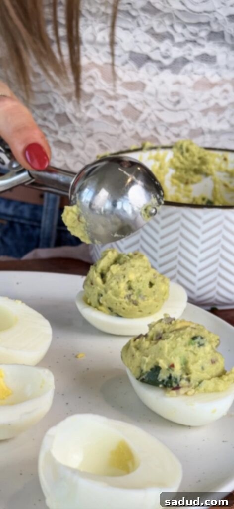 Finished guacamole deviled eggs garnished with cilantro and red pepper flakes.