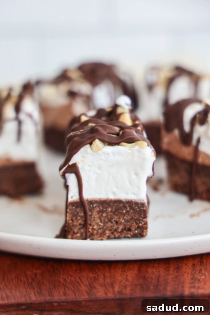 Close-up of Ice Cream Brownie Bites layers, showing the brownie base, two whipped topping layers, and chocolate coating
