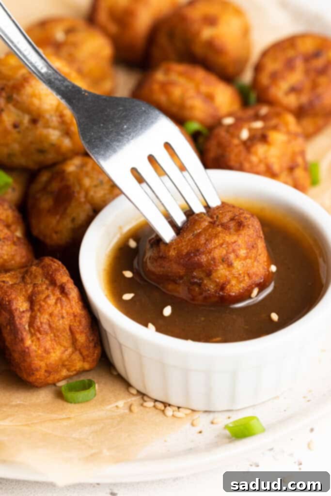 frozen meatballs in air fryer being dipped in teriyaki sauce