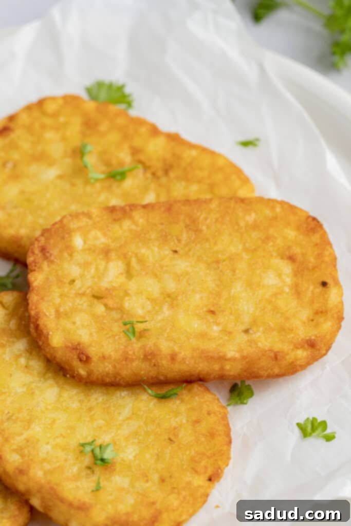 Freshly cooked, golden-brown hashbrowns from the air fryer, piled on a plate.