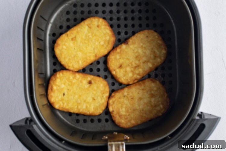 Crispy hashbrowns cooking in the air fryer, showing golden-brown perfection.