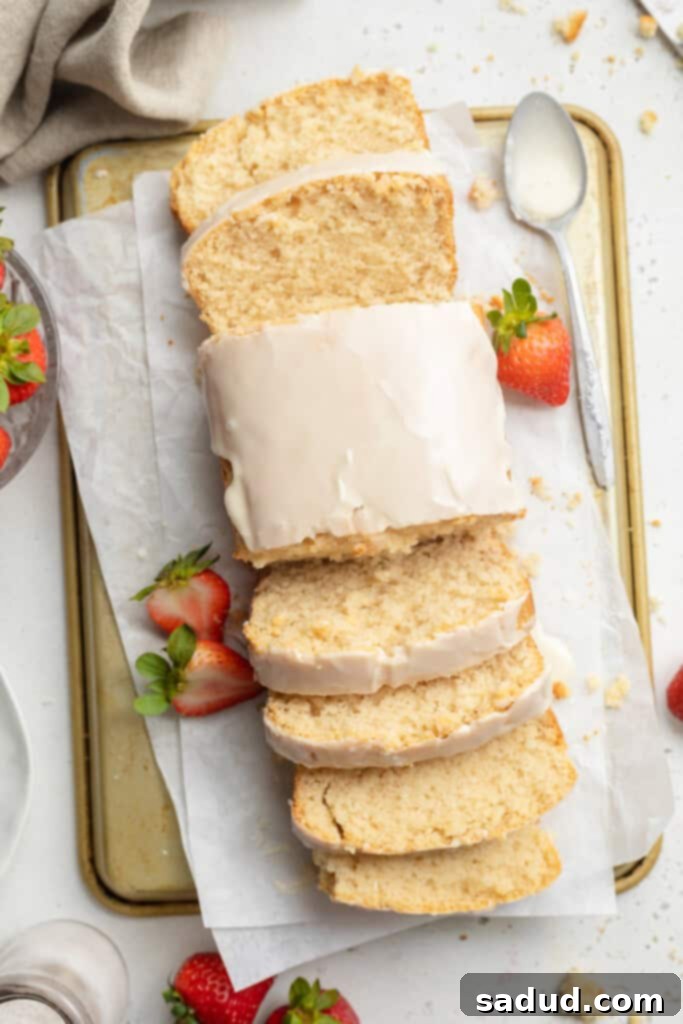 overhead image of vegan pound cake sliced on both ends, with fresh strawberries on the side